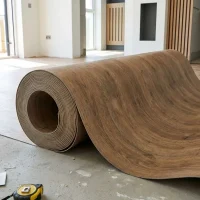 Rollo de piso vinílico tipo madera siendo instalado en una habitación, mostrando su flexibilidad y formato continuo