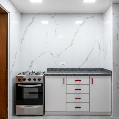 Cocina remodelada con revestimiento de wallpanel PVC marmoleado blanco y granito gres gris, ambiente moderno y limpio.