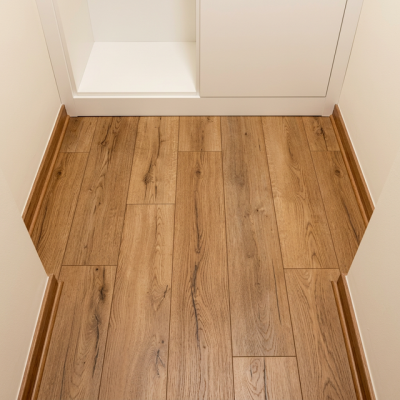 Detalle de piso laminado New Ardenas en tono roble cálido instalado en un vestidor con muebles blancos.