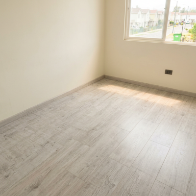 Dormitorio luminoso con piso flotante laminado Spruce Grey de Pisos Alemanes, acabado gris claro y vetas naturales.